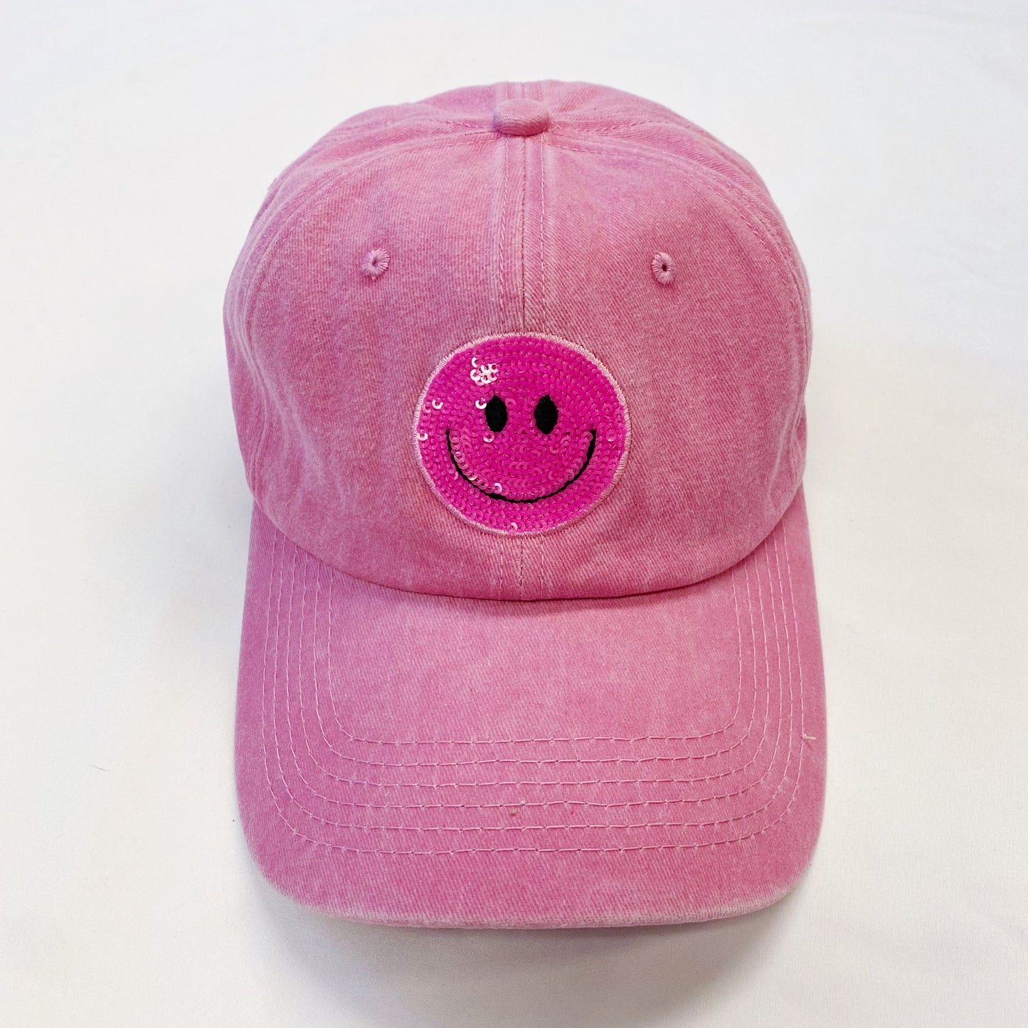 Pink smiley face cap with sequins for a playful, trendy look on a white background.