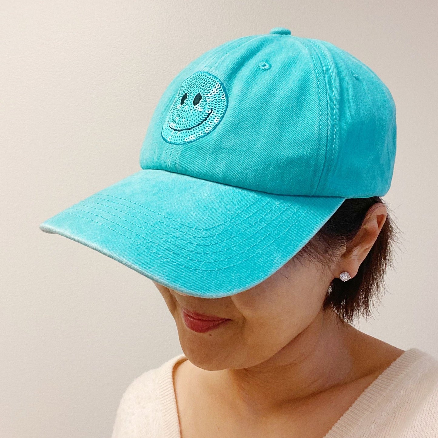 Turquoise baseball cap with a smiling face logo, perfect for casual outdoor activities and stylish fashion statements.