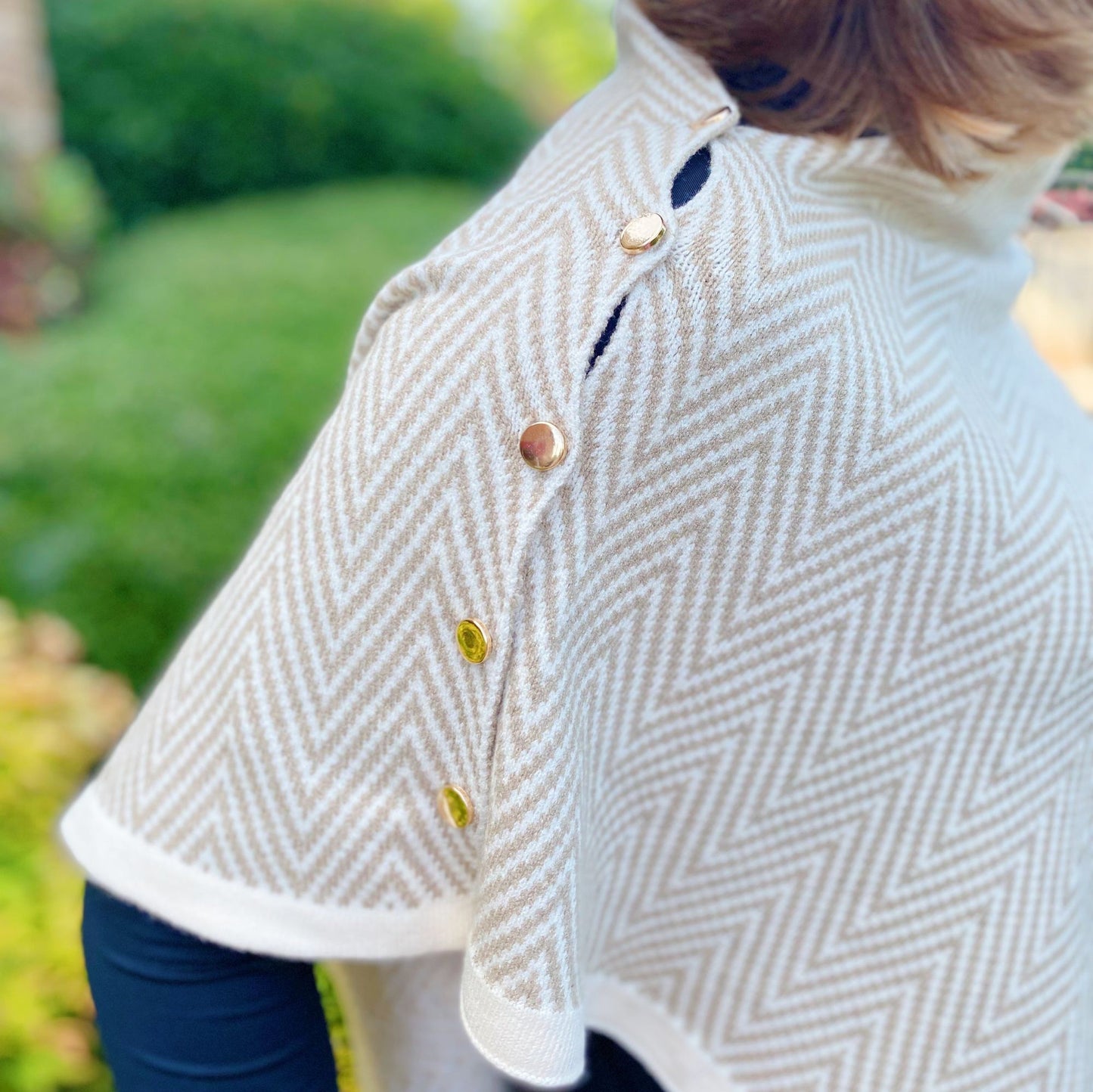 Elegant beige herringbone poncho with decorative gold and brass buttons, showcasing a stylish and cozy look for fall and winter fashion.