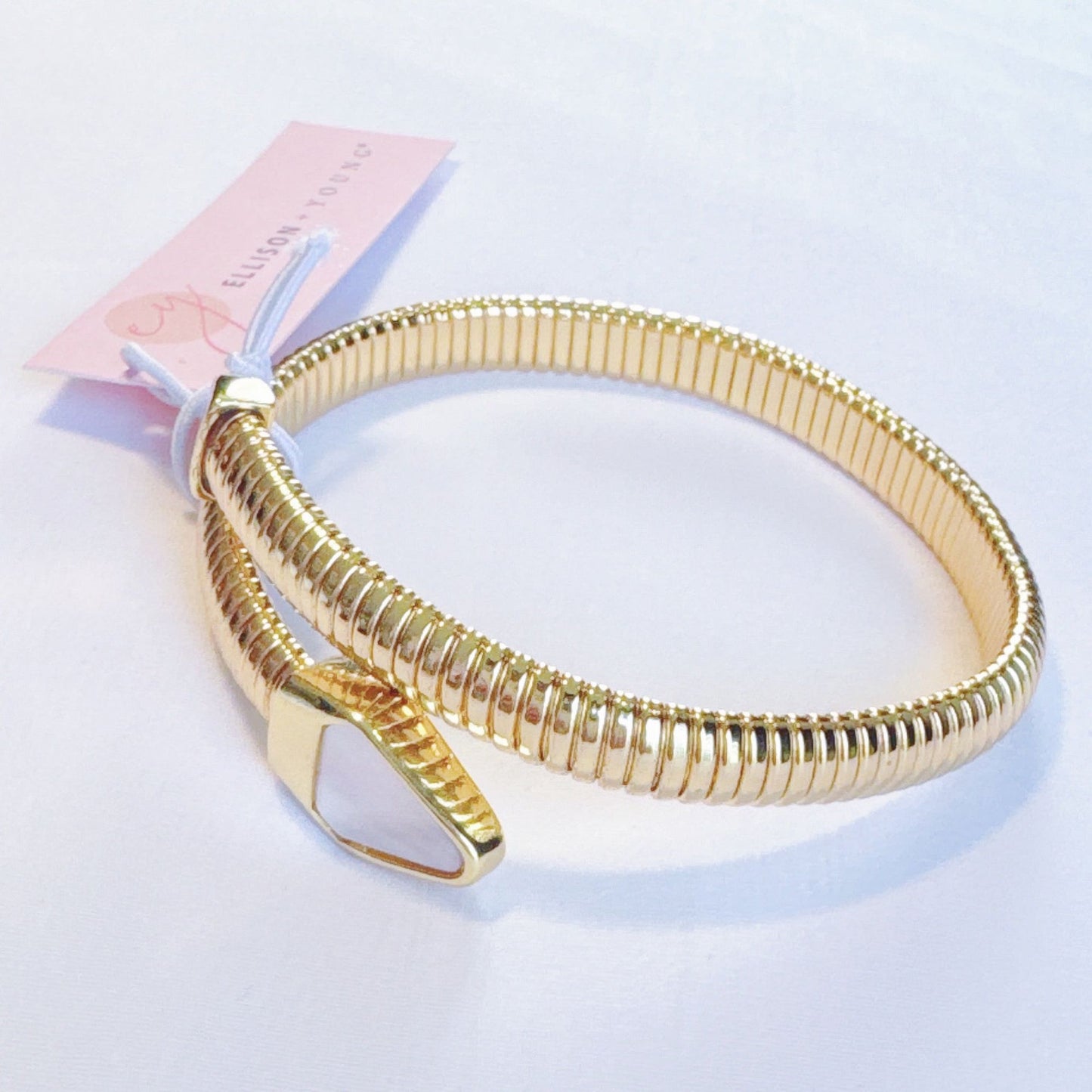 Gold coil bangle bracelet with a sleek design and adjustable clasp, featuring a tag from Ellison Young.