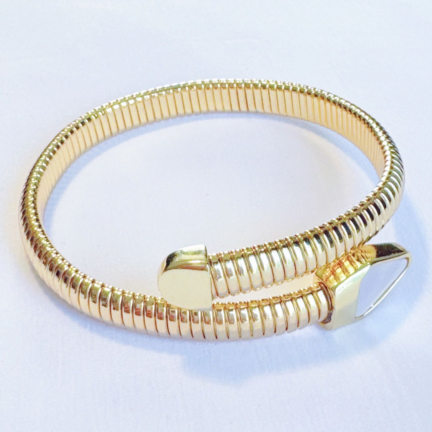 Elegant gold spiral bangle bracelet with a flexible design and a modern angular clasp, perfect for adding a stylish touch to any outfit.