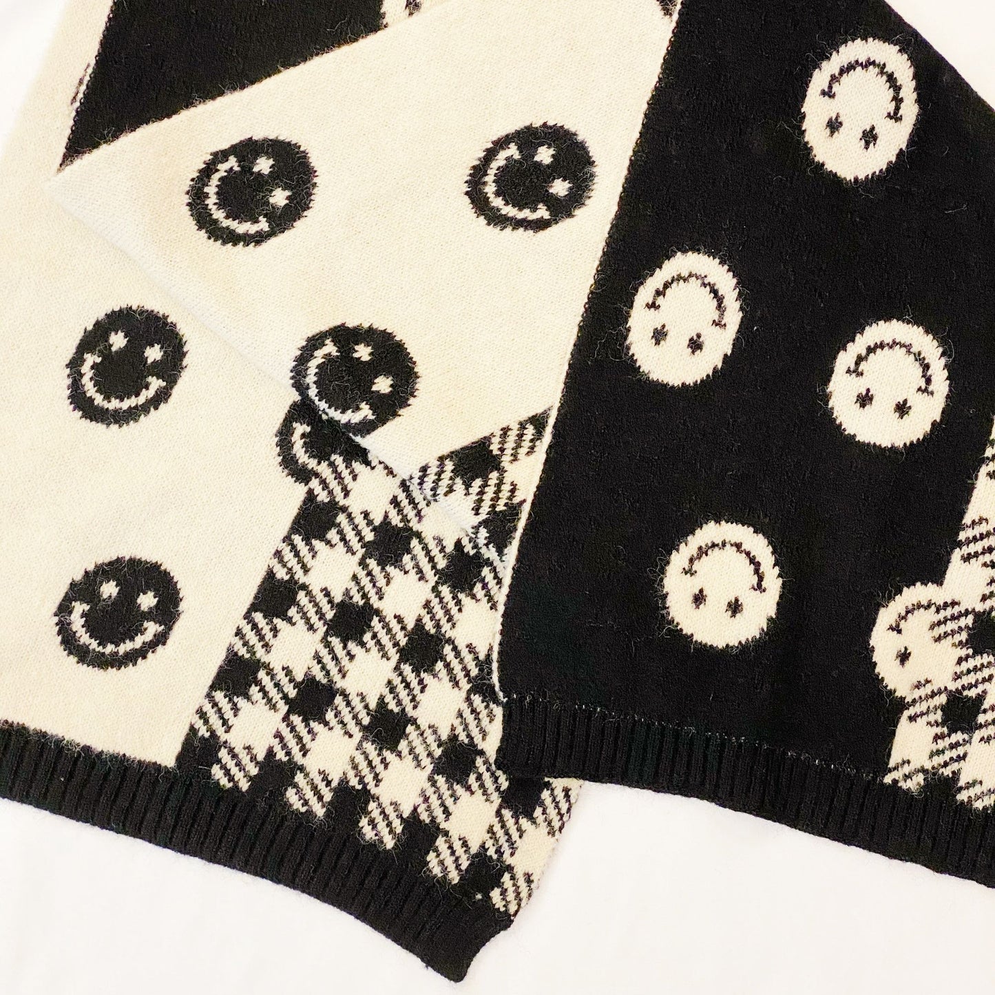 Black and white knit sweater featuring playful smiley face patterns and a classic houndstooth design, perfect for a stylish and cozy look.