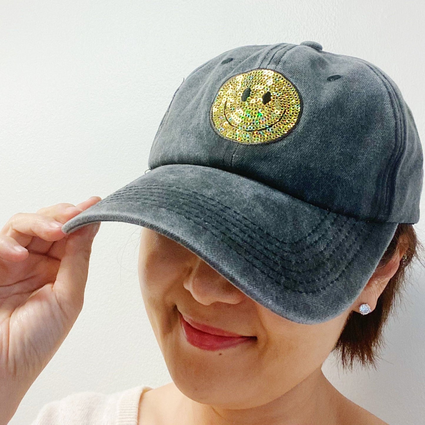 Stylish gray baseball cap with a sparkling gold rhinestone smiley face design, perfect for casual outfits and adding a fun touch to any look.