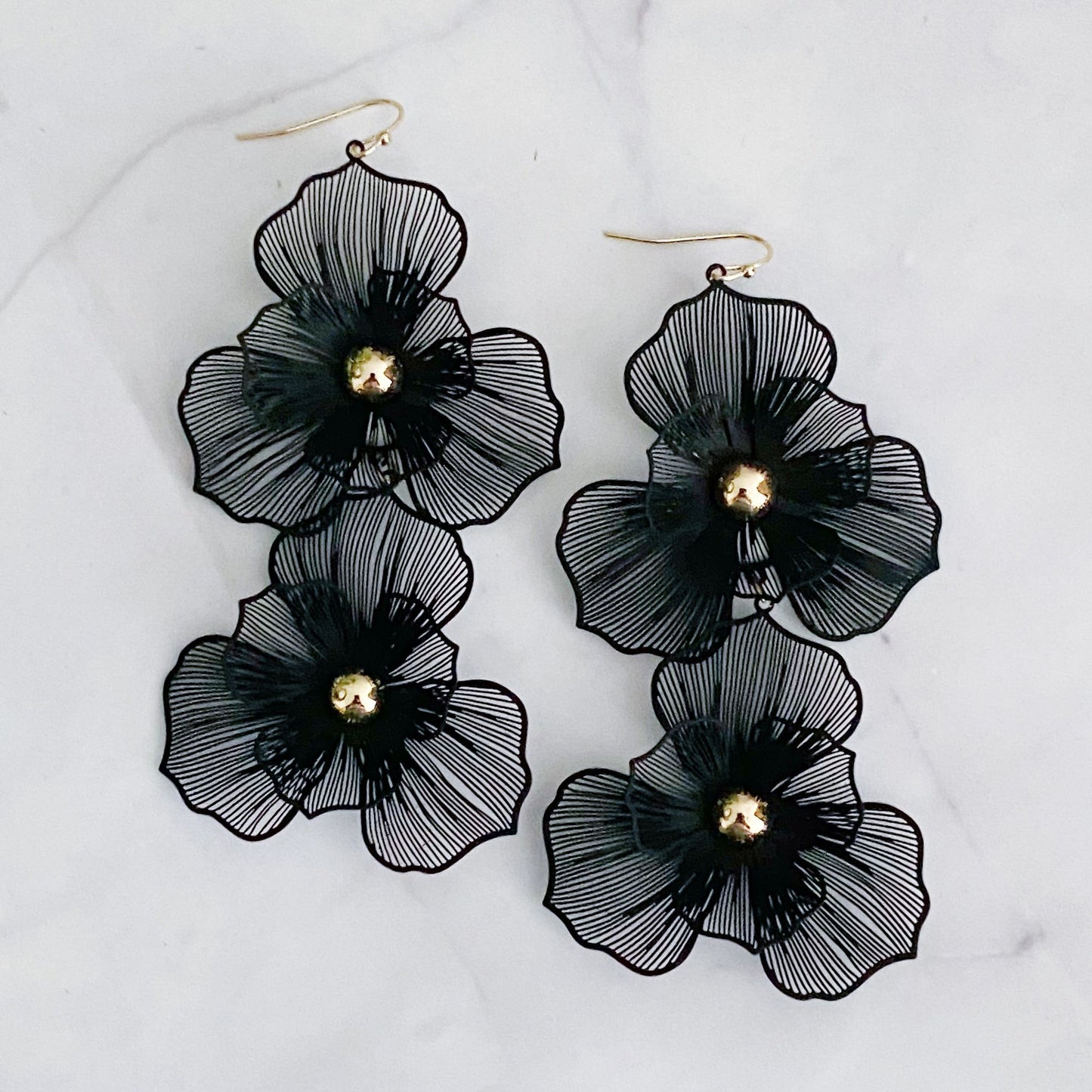 Black floral statement earrings with gold bead centers, featuring intricate layered petal designs, designed for a chic and elegant look.