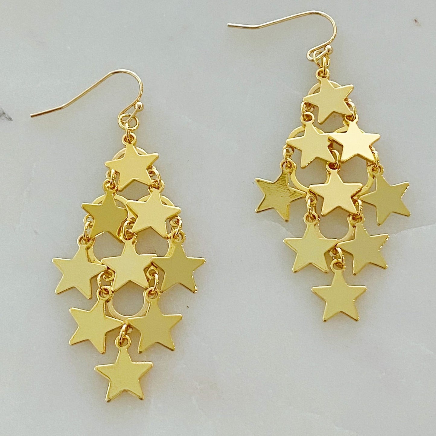 Gold star dangle earrings featuring multiple shiny star charms cascading from a delicate hook, perfect for adding a touch of glam to any outfit.