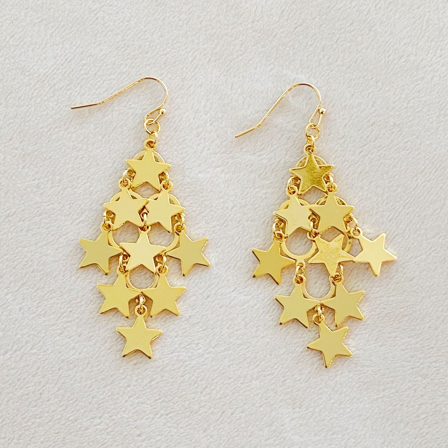 Gold star chandelier earrings featuring a cascading design of shiny, linked star charms.