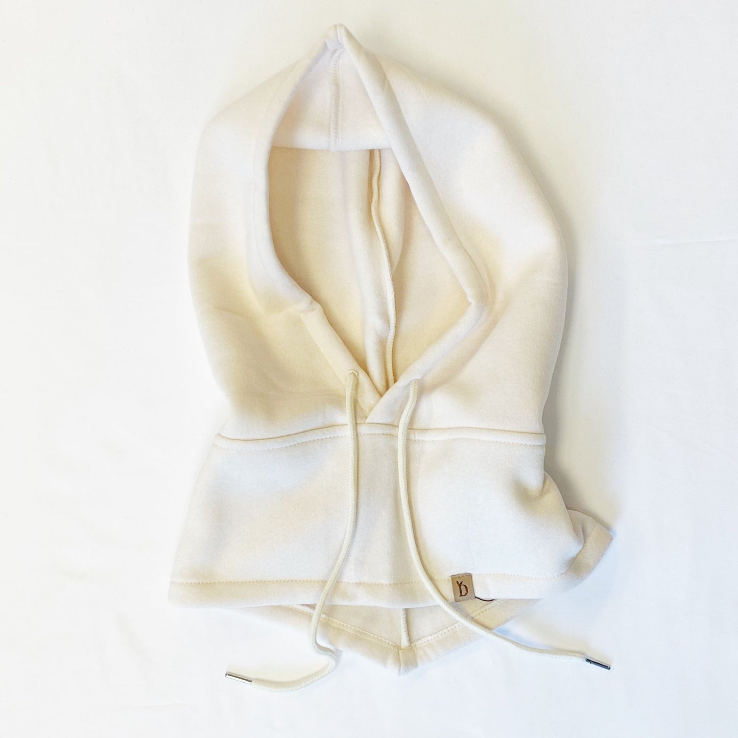 Cream-colored pullover hoodie with an oversized hood and drawstring, styled on a white background showcasing its relaxed fit and cozy design.