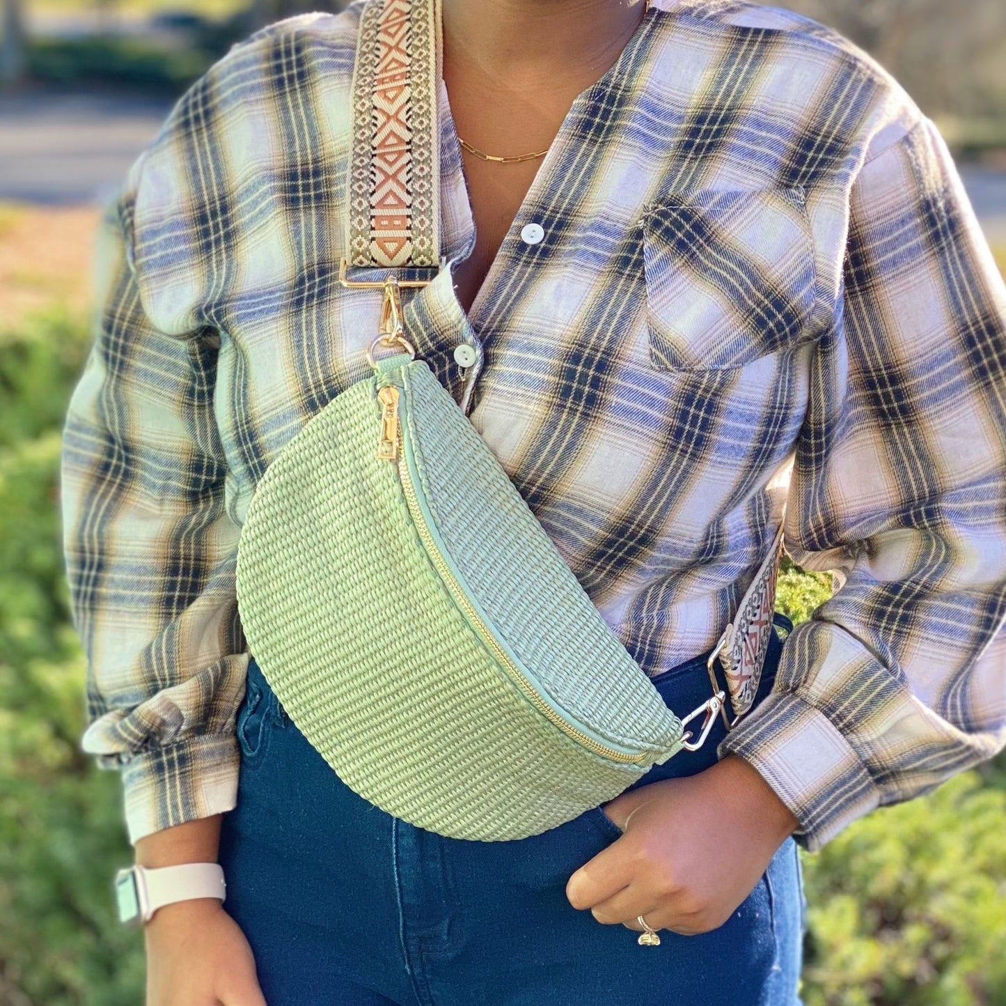 Fashionable mint green crossbody bag with textured fabric and decorative strap, worn by a model in a plaid shirt and denim jeans, showcasing casual style.