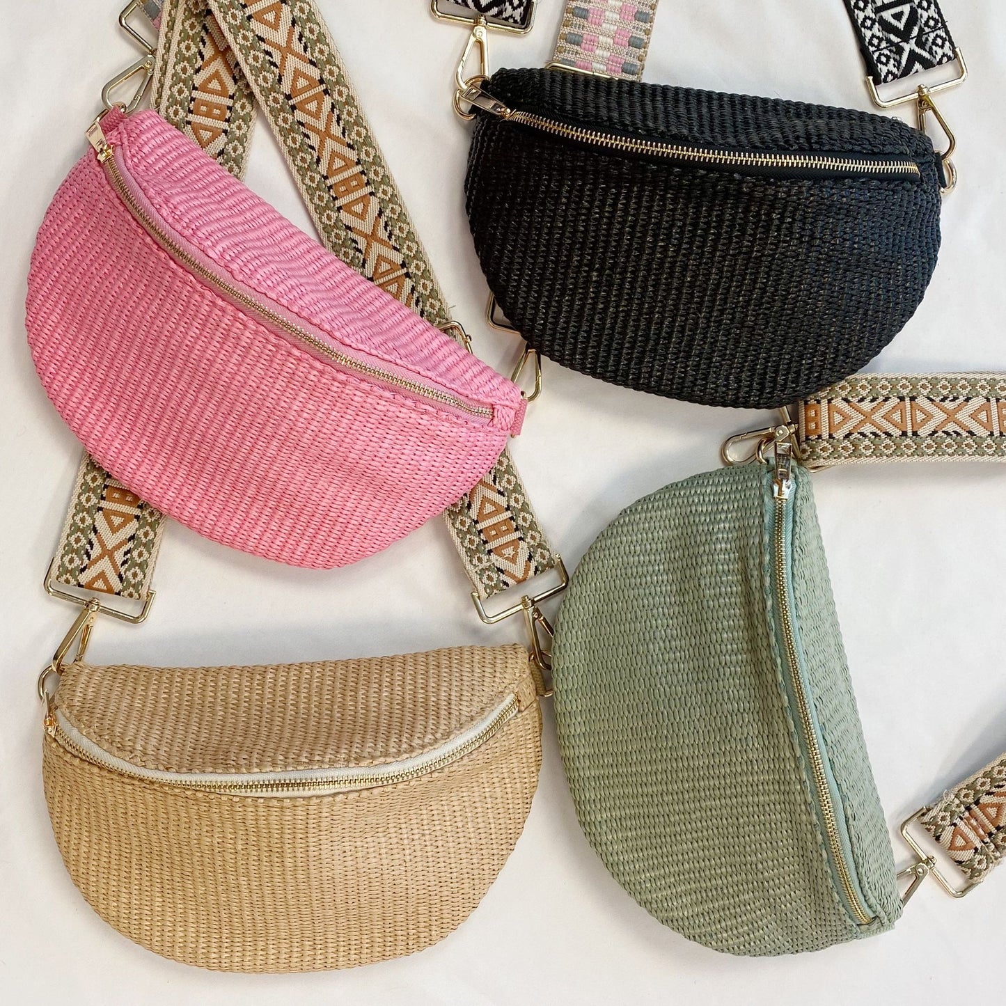 Colorful woven crossbody bags in pink, black, green, and beige with gold zippers and patterned straps arranged on a white background.