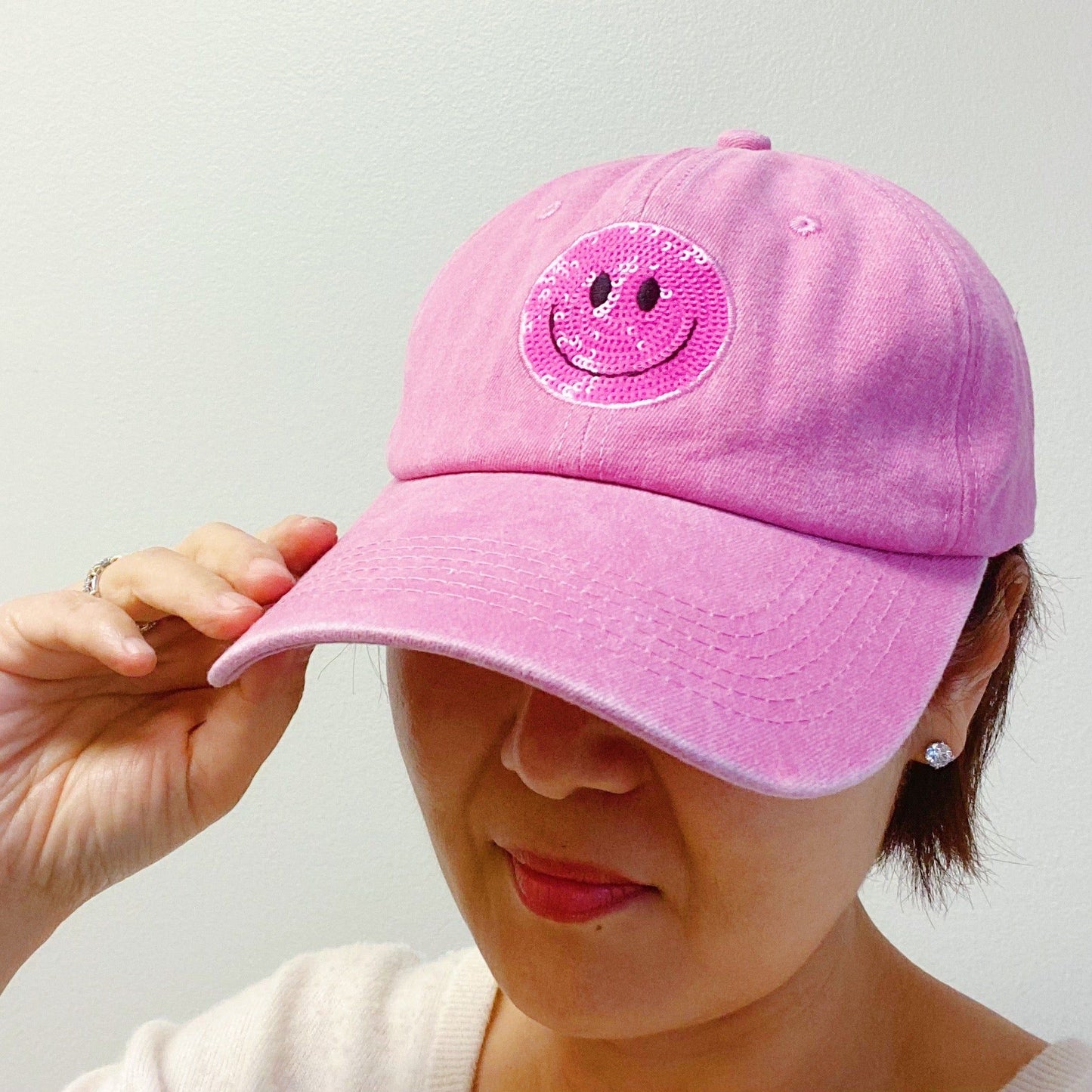 Pink cap with a sparkling smiley face patch, perfect for adding a fun touch to any outfit.