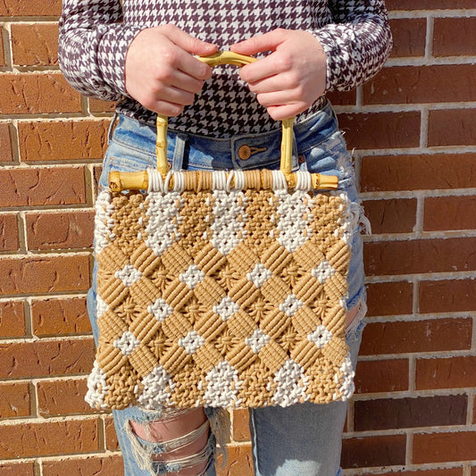 Stylish macrame handbag woven in natural tones, featuring a bamboo handle, perfect for a trendy look in any season.