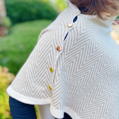 Elegant beige herringbone poncho with decorative gold and brass buttons, showcasing a stylish and cozy look for fall and winter fashion.