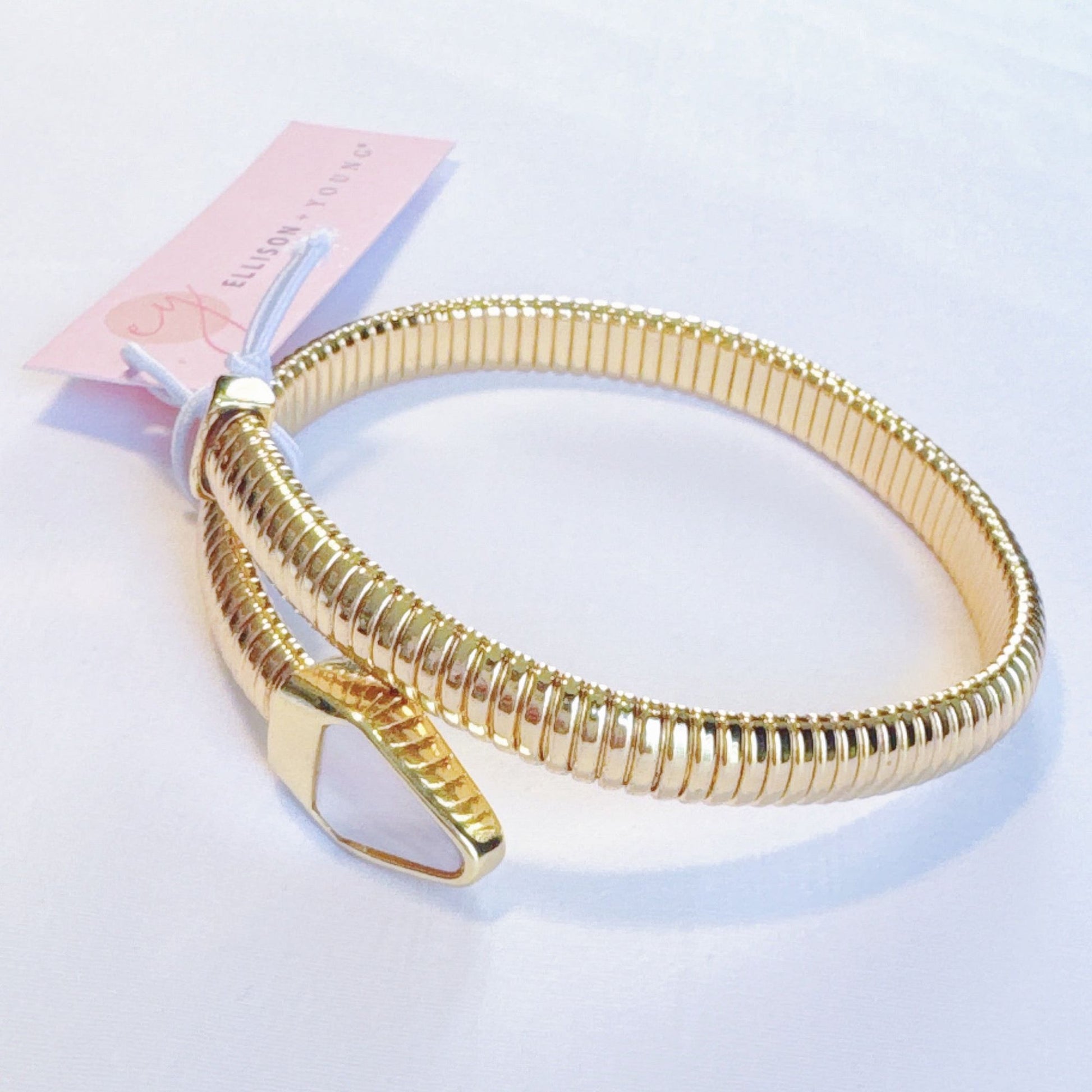 Gold coil bangle bracelet with a sleek design and adjustable clasp, featuring a tag from Ellison Young.