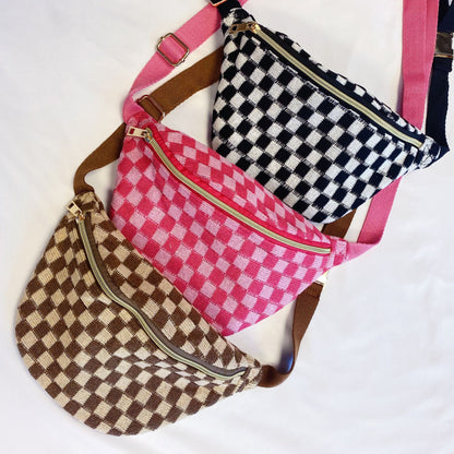 Three stylish checkered fanny packs in pink, black, and brown colors, featuring gold zippers and adjustable straps, displayed on a white background.