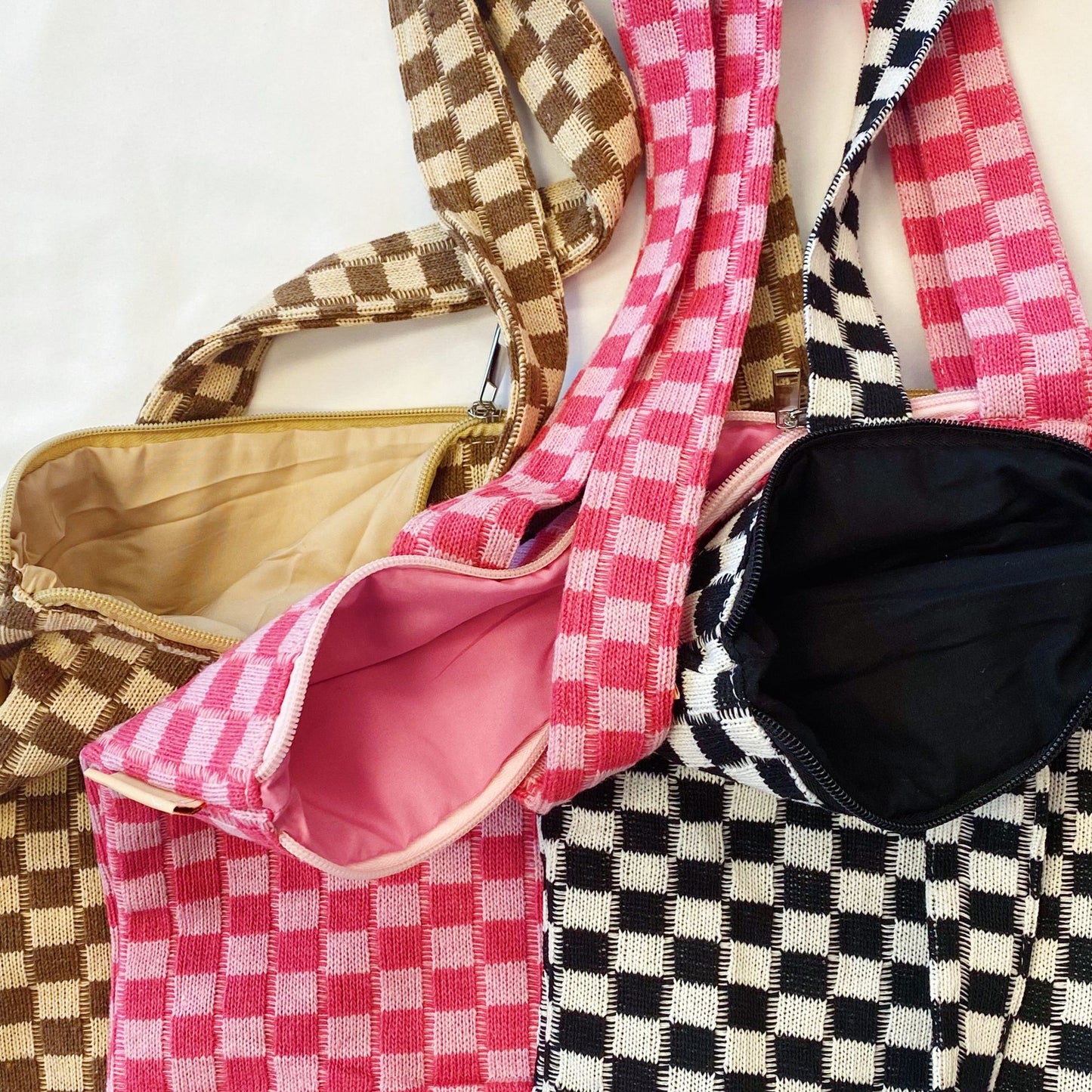 Colorful checkered tote bags in pink, brown, and black with varying interior linings displayed on a white background.
