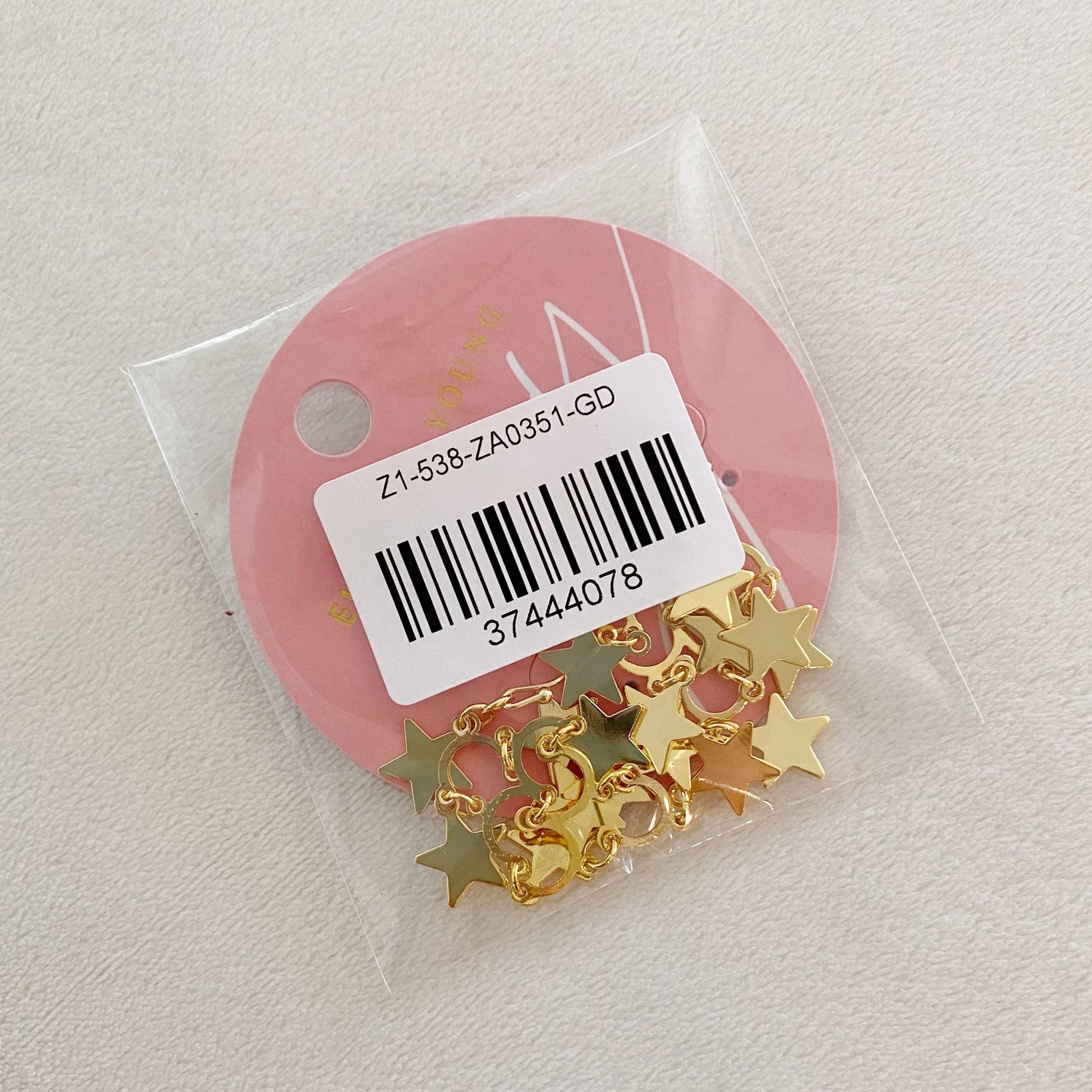 Gold star-shaped charms packaged in a clear plastic bag with a pink circular label, ideal for jewelry making and craft projects.