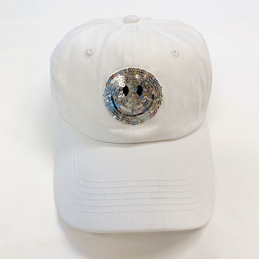 White baseball cap featuring a sparkly silver smiley face sequin design on the front, perfect for casual wear and adding a fun touch to any outfit.