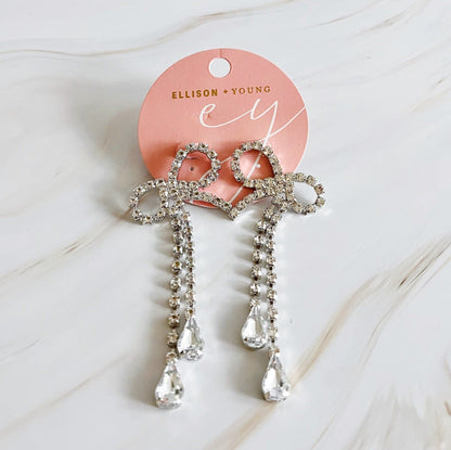 Elegant rhinestone bow hair clips with dangling crystal accents on a pink branded card by Ellison + Young.