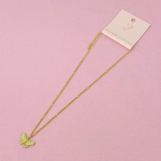 Gold butterfly pendant necklace on a delicate chain displayed on a pink background with a branded tag.