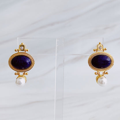 Elegant gold-tone earrings featuring deep blue lapis lazuli stones accompanied by a pearl drop, perfect for adding a touch of sophistication to any outfit.