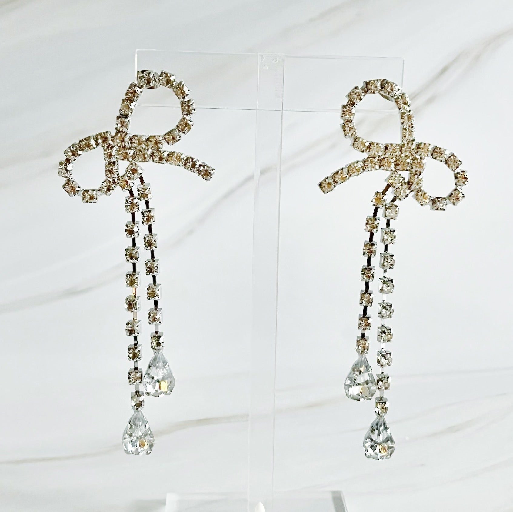 Elegant crystal bow earrings with dangling rhinestones and teardrop gems, perfect for formal occasions or adding sparkle to any outfit.