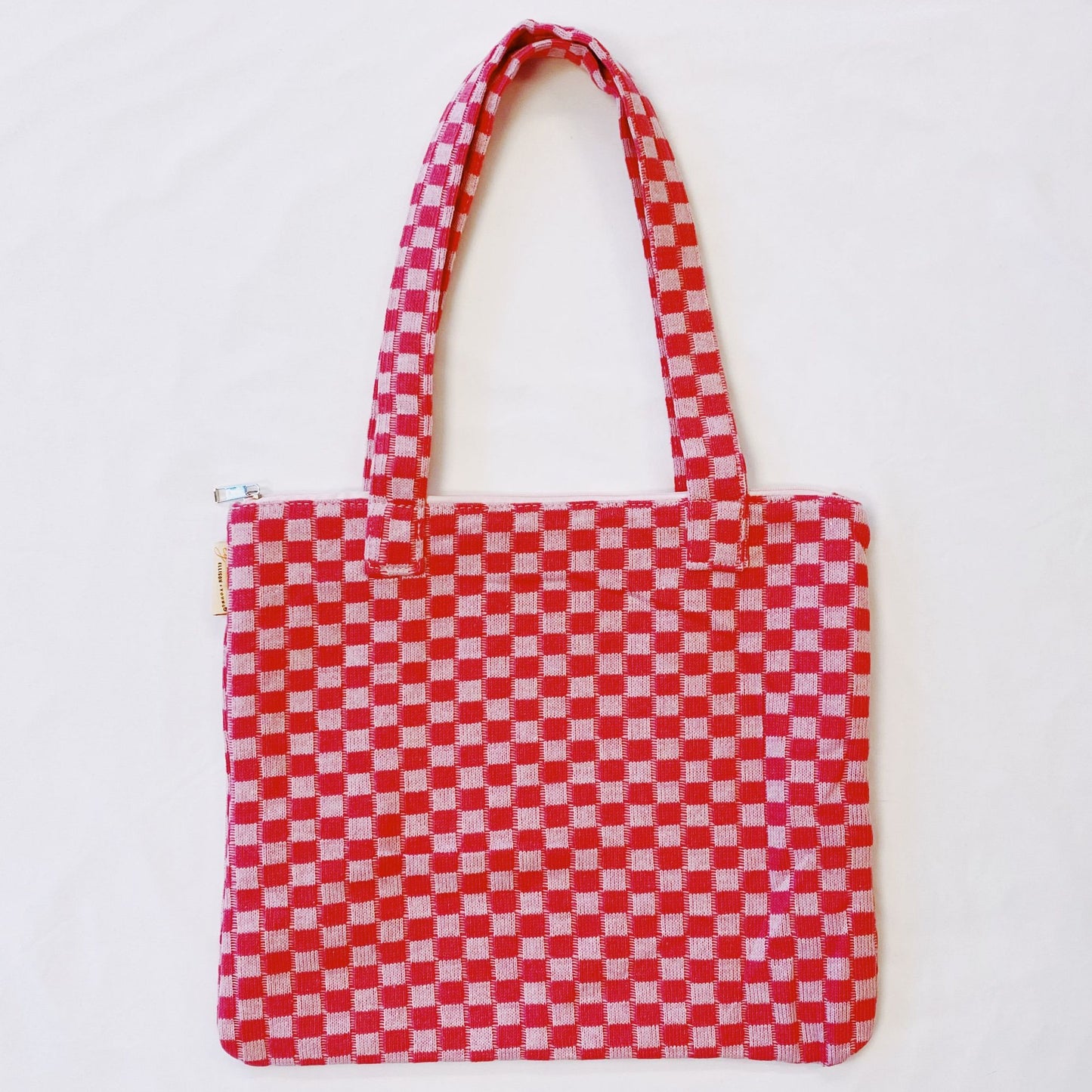 Red and white checkered tote bag with two sturdy handles and zip closure, perfect for shopping or daily use.