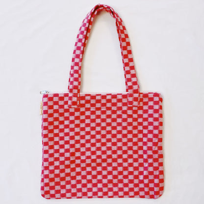 Red and white checkered tote bag with two sturdy handles and zip closure, perfect for shopping or daily use.