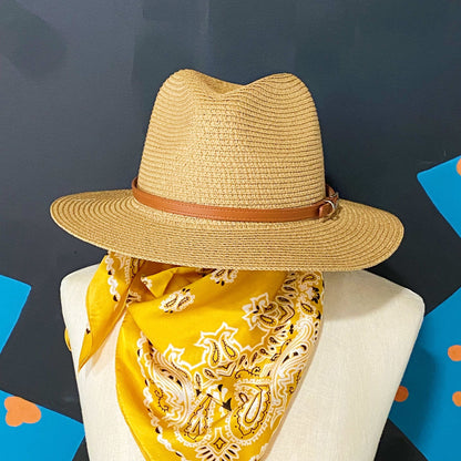 Straw wide-brimmed hat with a brown leather band displayed on a mannequin, paired with a bright yellow paisley bandana, against a colorful background.