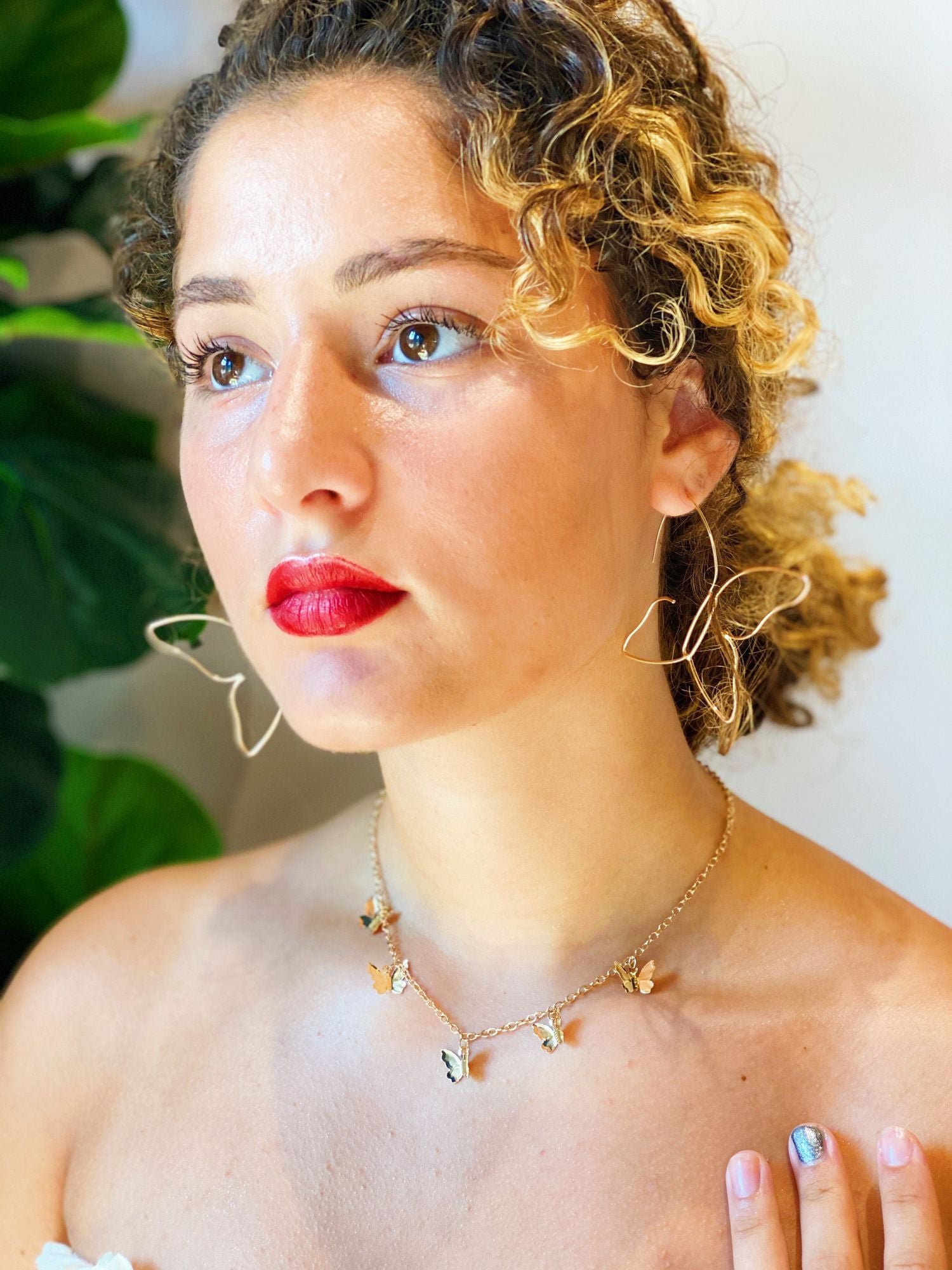 Close-up of a stylish butterfly charm necklace on a model, showcasing a delicate gold chain with colorful butterfly pendants, perfect for adding a whimsical touch to any outfit.