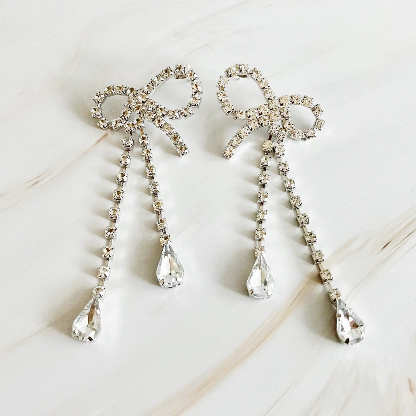 Sparkling silver bow earrings adorned with clear crystal drops, perfect for formal occasions and elegant outfits.