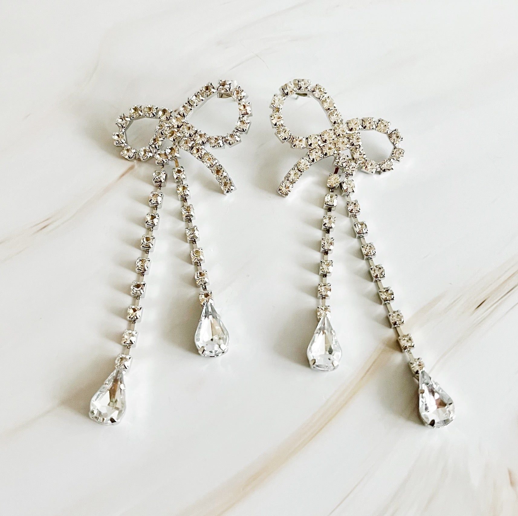 Sparkling silver bow earrings adorned with clear crystal drops, perfect for formal occasions and elegant outfits.