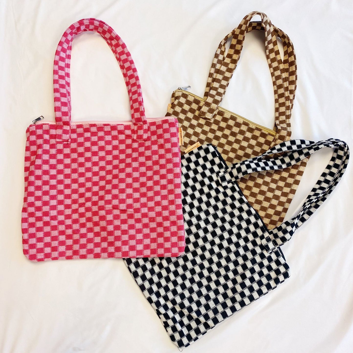 Colorful checked tote bags in pink, brown, and black on a white background, showcasing stylish handles and patterns perfect for casual outings or everyday use.