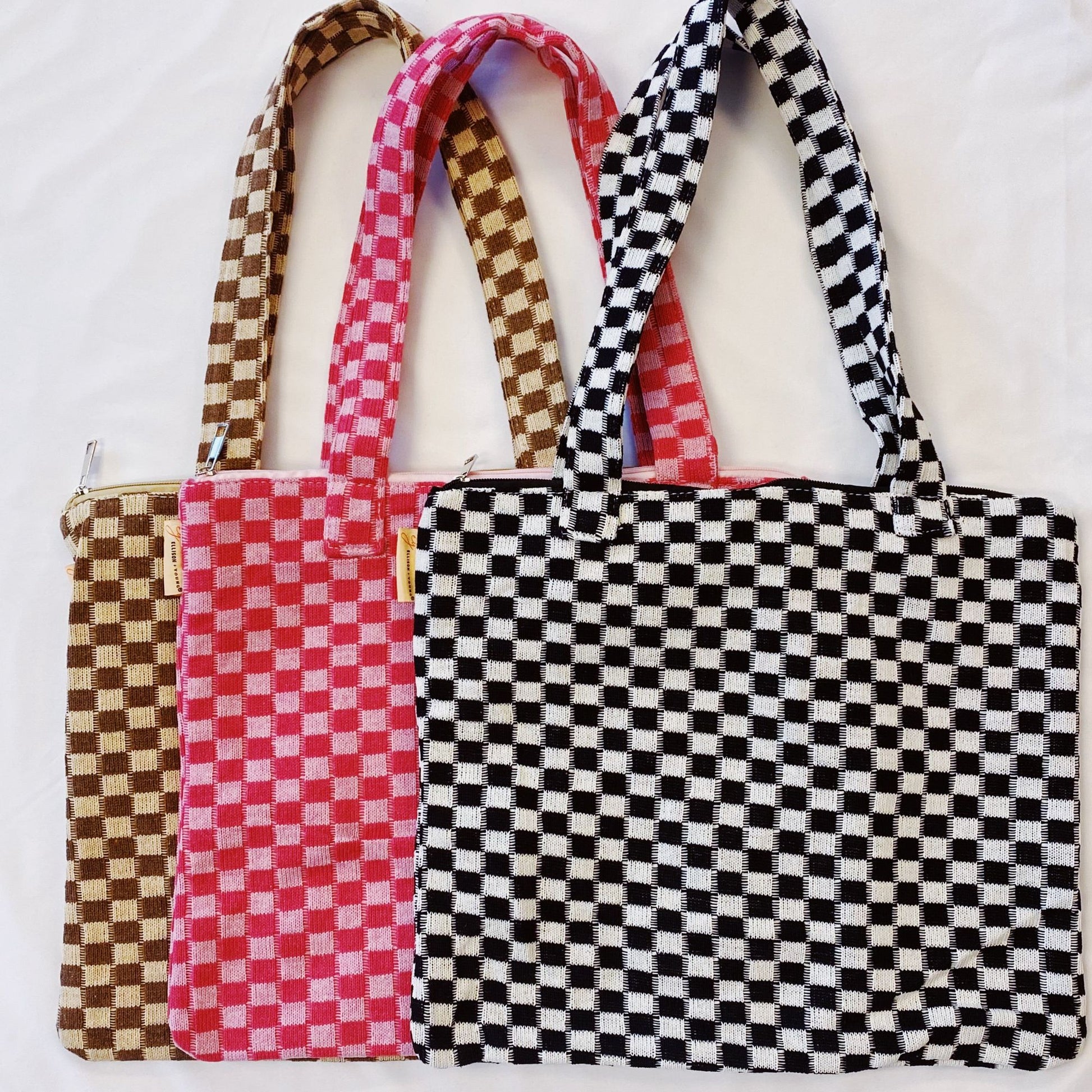 Set of three stylish checkerboard pattern tote bags in brown, pink, and black, featuring zip closure and sturdy handles.