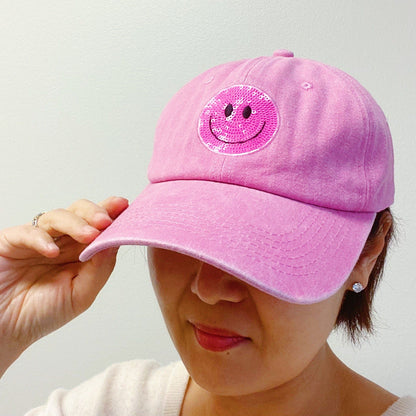 Pink cap with a sparkling smiley face patch, perfect for adding a fun touch to any outfit.
