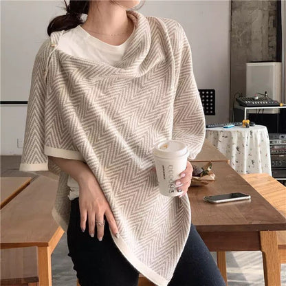 Casual woman in a stylish herringbone-patterned poncho, holding a coffee cup, showcasing a cozy outfit in a modern indoor setting.
