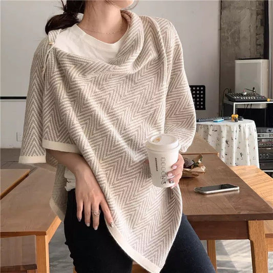 Casual woman in a stylish herringbone-patterned poncho, holding a coffee cup, showcasing a cozy outfit in a modern indoor setting.
