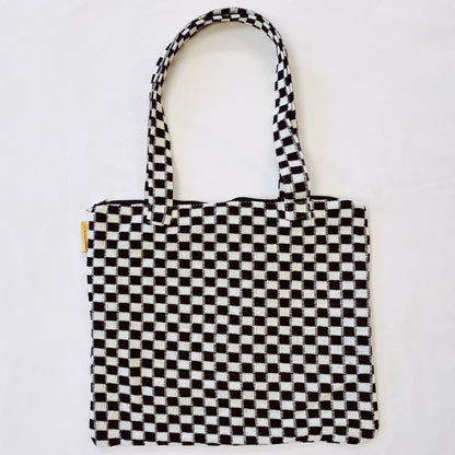 Black and white checkered tote bag with sturdy handles and a zipper closure, perfect for everyday use and stylish shopping.